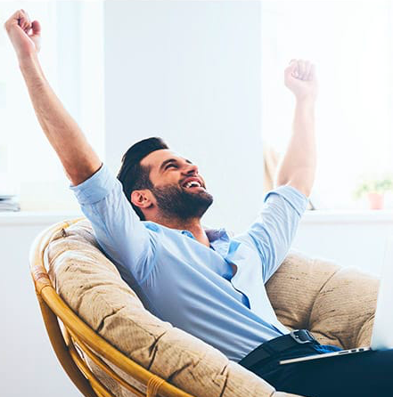 Zinzino partner celebrating success with arms in the air sitting back in an armchair