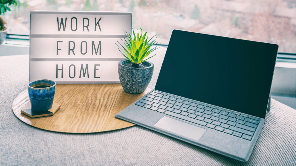 laptop on desk with 'work from home' sign next to it